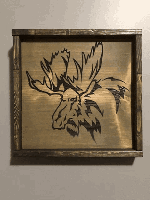 a picture of a moose in a wooden frame on a white wall