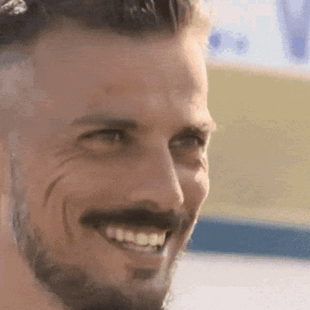 a close up of a man 's face with a beard and mustache smiling