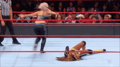 a woman is wrestling another woman in a wrestling ring while a referee watches .