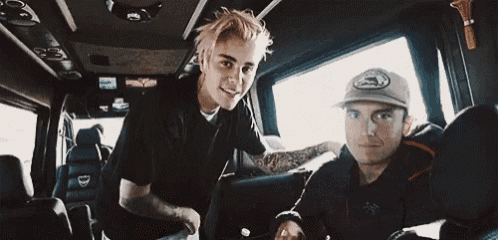 two men are sitting in the back seat of a car and smiling .