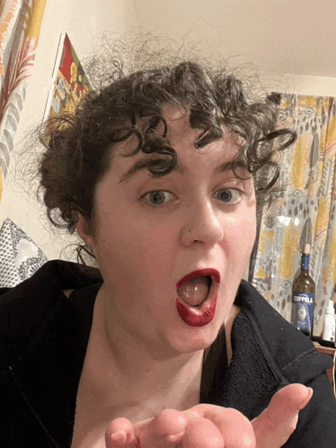 a woman wearing red lipstick is making a funny face in front of a bottle of coppola