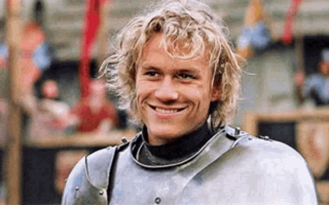 a man in a knight 's armor is smiling for the camera .