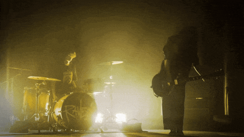 a man playing a guitar in front of a drum set that says riff