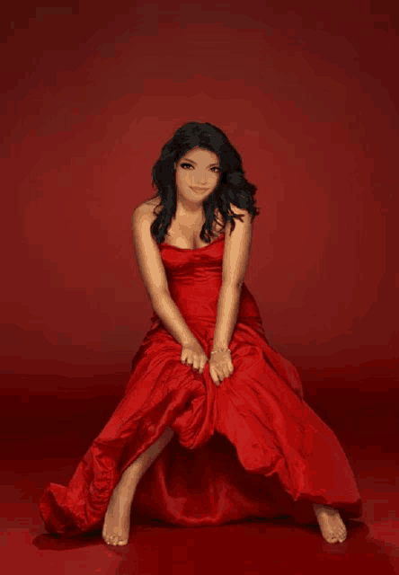 a woman in a red dress sits on a red background