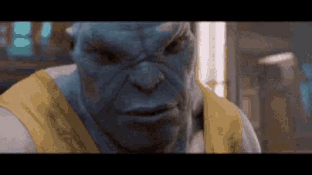 a close up of a blue monster wearing a yellow shirt and looking at the camera .