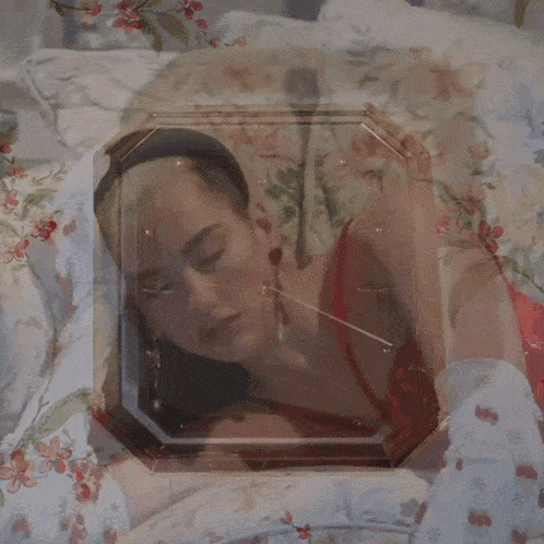 a woman in a red dress is laying on a couch with flowers on it