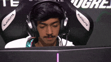 a man wearing blacklyte headphones sits in front of a monitor