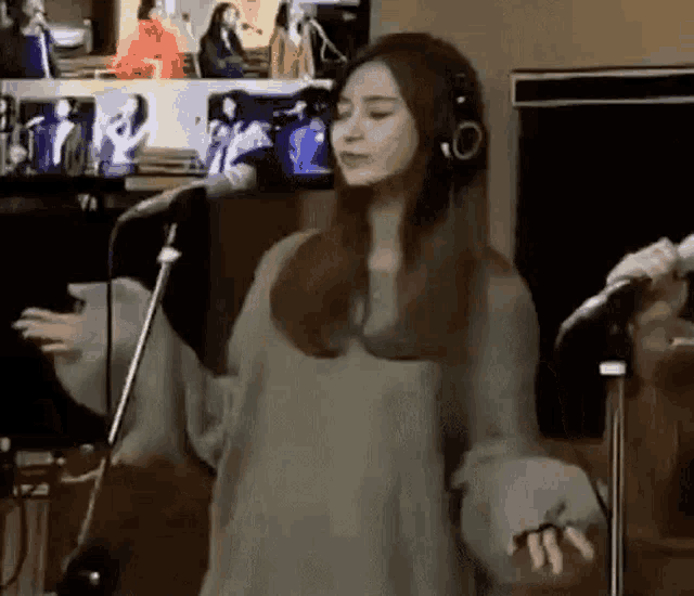 a woman wearing headphones is standing in front of a microphone .