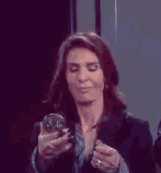 a woman is applying lipstick and looking at herself in the mirror .