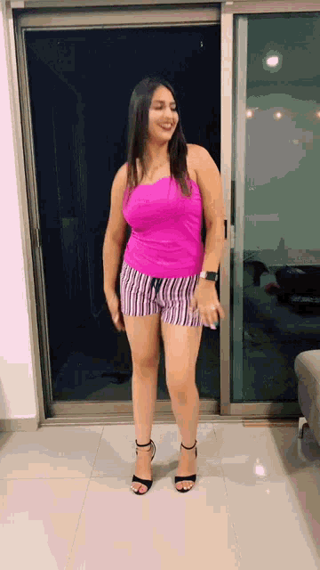 a woman in a pink tank top and shorts is standing in front of a glass door