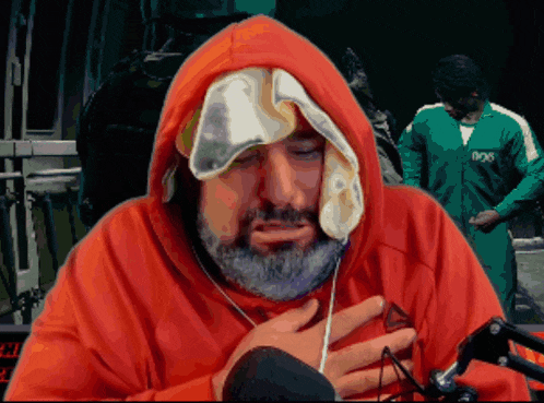 a man with a beard wearing a red hoodie with a towel over his head