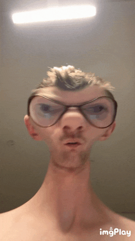 a man without a shirt is making a funny face with glasses on