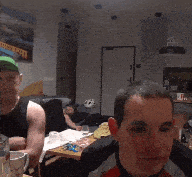 a man wearing a green hat with a bike on it is talking to another man