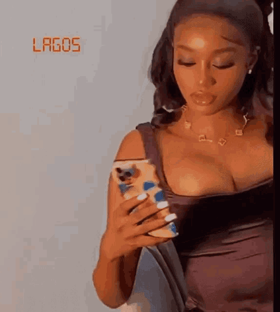 a woman in a purple dress is holding a cell phone in her right hand .