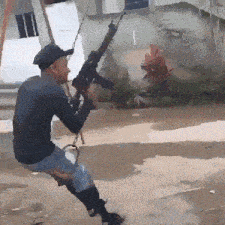 a man is swinging on a swing with a gun in his hand