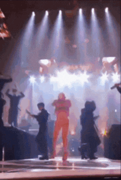a group of people are dancing on a stage with lights