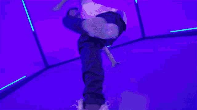 a man is sitting on the floor in a room with purple lights behind him .
