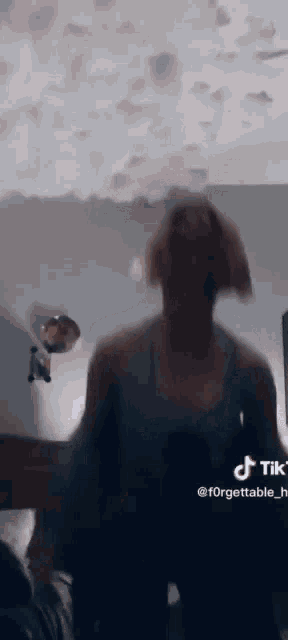 a woman is standing in front of a mirror in a bedroom .