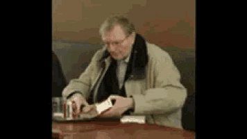 a man is sitting at a table with a can of soda in his hand .