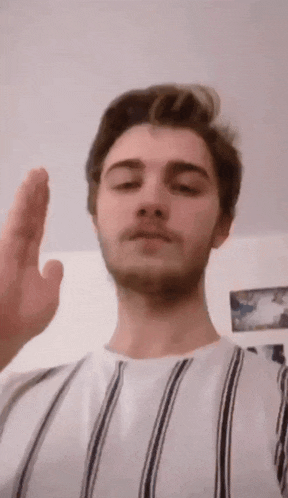 a man wearing a striped shirt is giving the middle finger