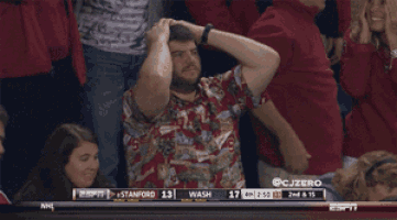 a man in a hawaiian shirt is watching a game between stanford and washington