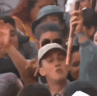 a group of people are standing in a crowd and one of them is holding a stick in his hand .