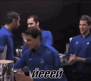 a man in a blue shirt is holding a trophy in his hands while another man stands behind him .