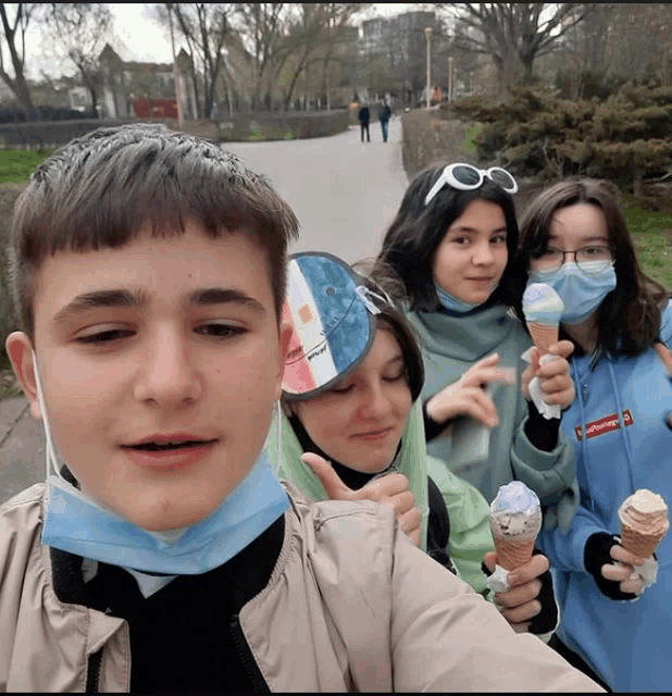 a boy wearing a mask holds an ice cream cone