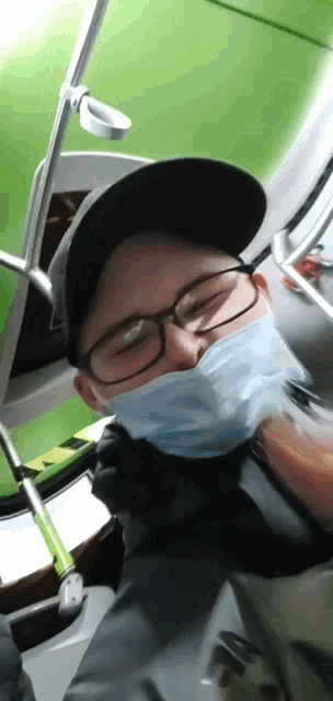a man wearing a face mask and glasses is sitting on a bus