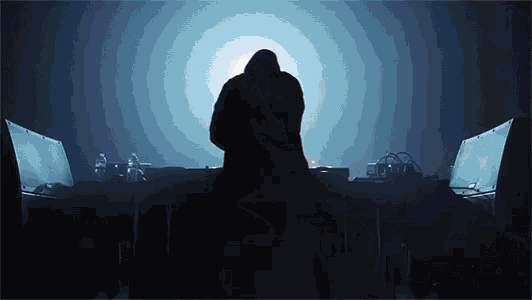 a silhouette of a man in a hooded jacket standing in front of a dj booth