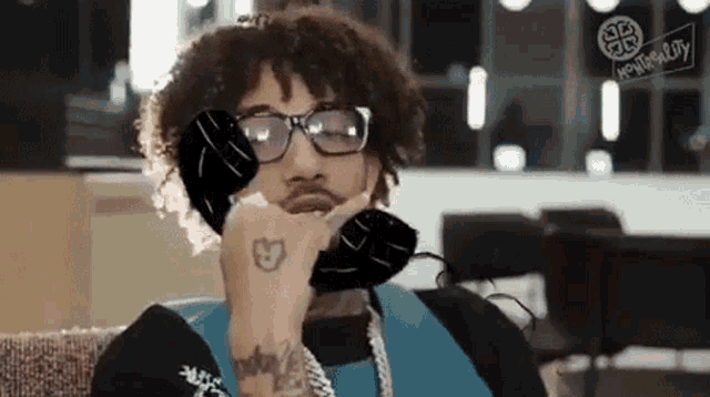 a man wearing glasses is talking on a phone .