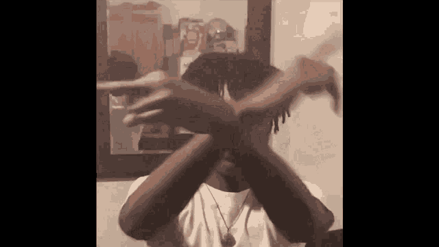 a man in a white shirt is making a cross with his hands .