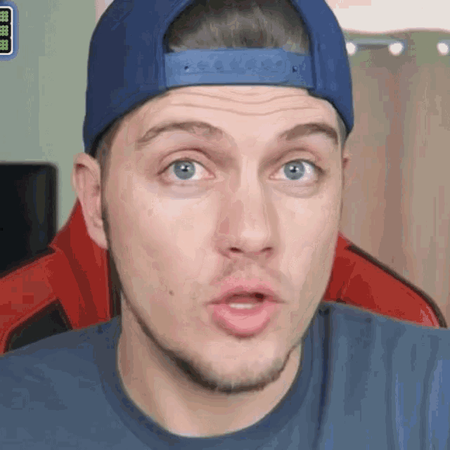 a man wearing a blue hat and a blue shirt is making a surprised face