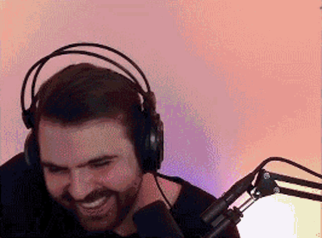 a man with a beard wearing headphones and a microphone is smiling .