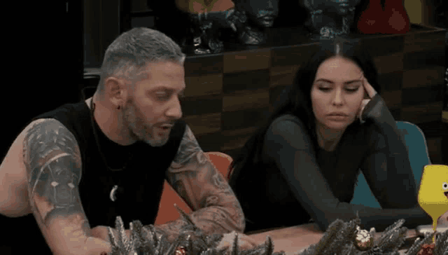 a man and a woman are sitting at a table with christmas decorations