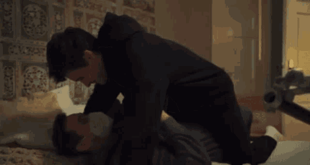 a man in a black hoodie is laying on top of another man in a grey shirt