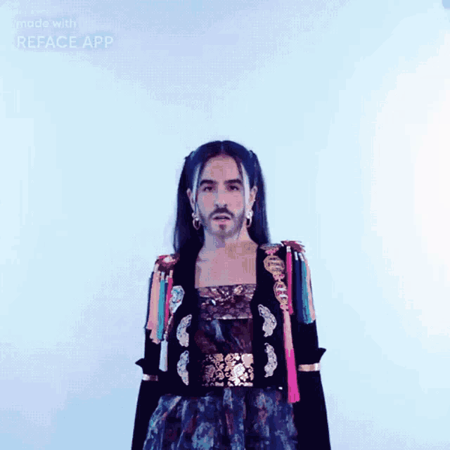 a man with long hair and a beard is standing in front of a blue background