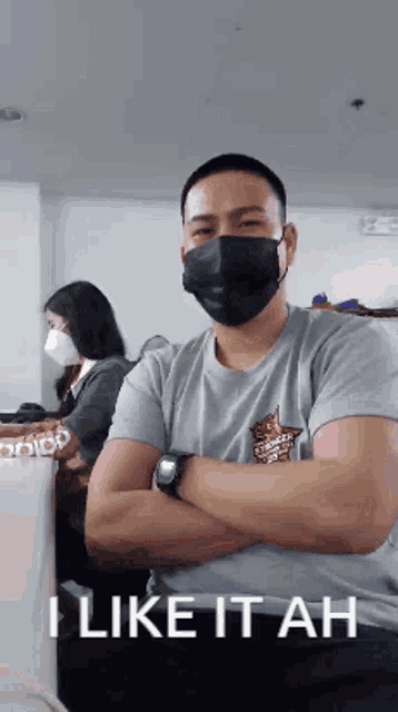 a man wearing a mask is standing with his arms crossed and says " i like it ah "