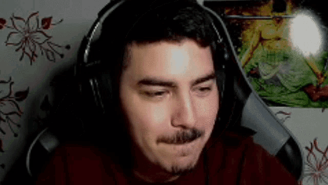 a man with a mustache and headphones is sitting in a chair .