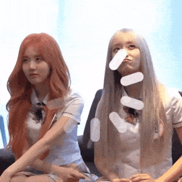 two girls in school uniforms are sitting next to each other on a couch