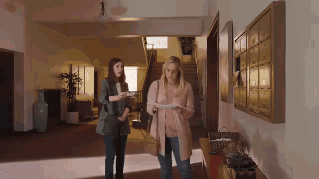 two women standing next to each other in a hallway