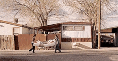 a man and a woman are walking down the street carrying a mattress .