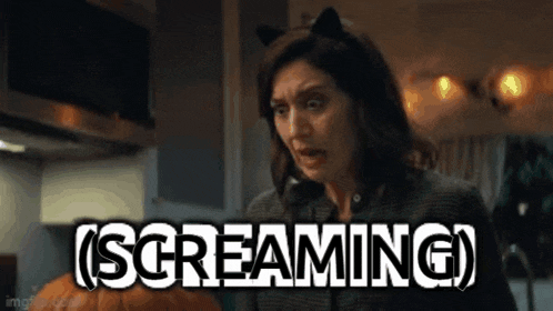 a woman wearing cat ears is screaming while holding a pumpkin .