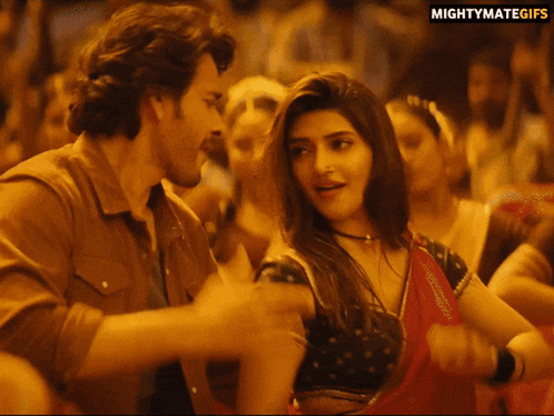 a man and woman are dancing in a crowd with mightymategifs in the corner