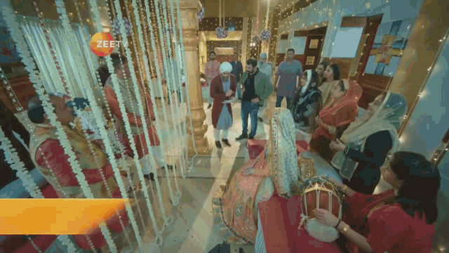 a group of people standing around a bride and groom with a zee tv logo in the corner