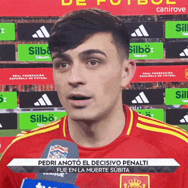 a man wearing a red shirt with yellow stripes is talking into a microphone