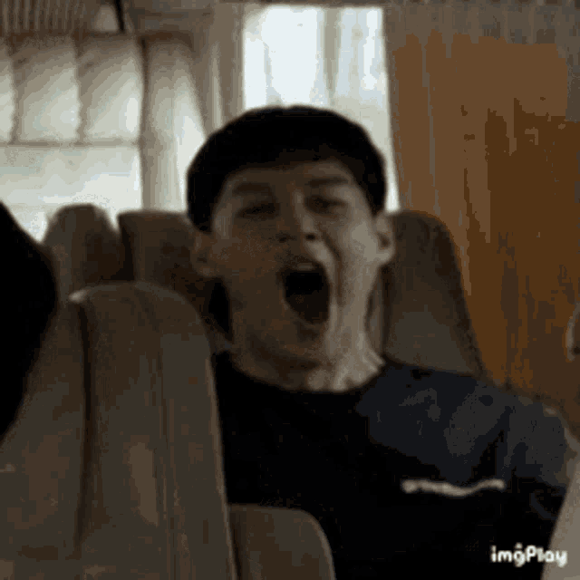 a man is yawning while sitting in a plane seat .