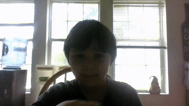 a boy is sitting in front of a window with a sign on the wall that says kitchen