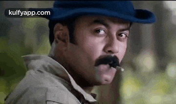 a man with a hat and a mustache is smoking a cigarette .