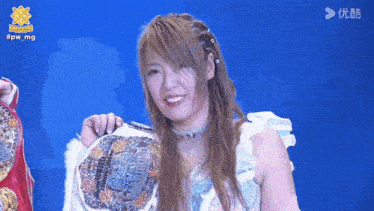 a woman holding a wrestling belt with the hashtag #pwmg behind her